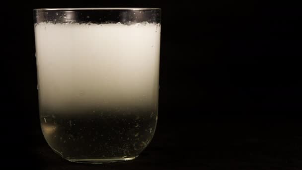 Каламутна біла вода, яка стає прозорою в склянці з усіма бульбашками, що піднімаються вгору, видно в зупинці проміжок часу руху — стокове відео