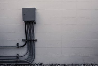 Elektrik kutusu ve boru hattı bağlantısı ile beyaz tuğla duvar