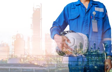 Technician stand hand holding safety helmet with blue uniform on petrochemical industrial background, Double exposure clipart