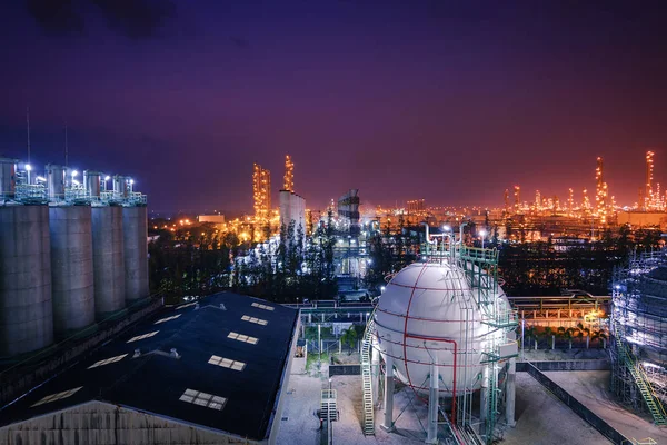 Storage tanks in warehouse with glitter lighting of petrochemical estate on background