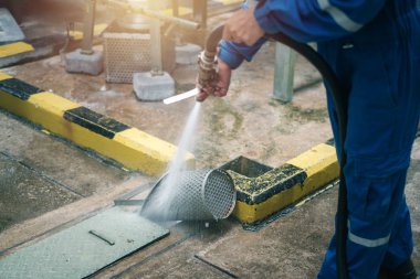 Worker cleaning bucket strainer in industrial plant