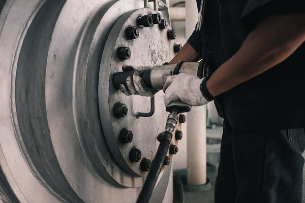 Mechanic hand holding tool tighten bolt and nut open manhole of vessel in factory