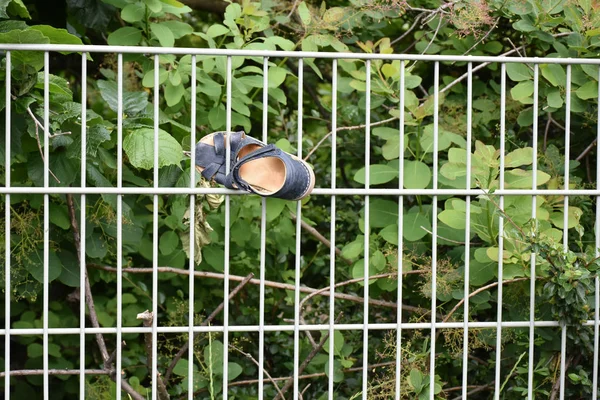 Small shoe stucked in metallic fence