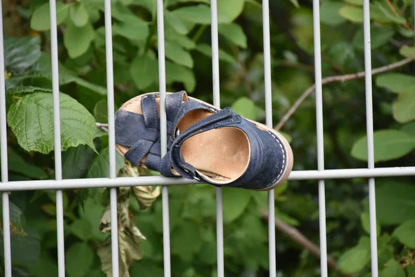 Small shoe stucked in metallic fence
