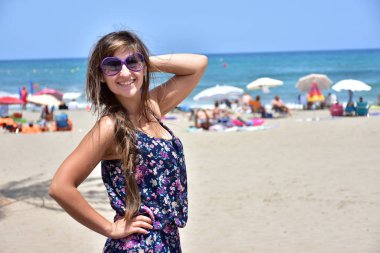 Denizin arka planında güneş gözlüklü kız