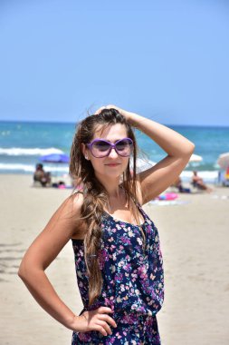 Denizin arka planında güneş gözlüklü kız