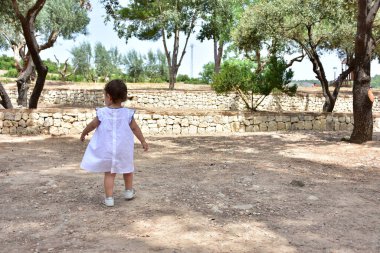 Manzaranın arka planında küçük bir çocuk yürüyor.,