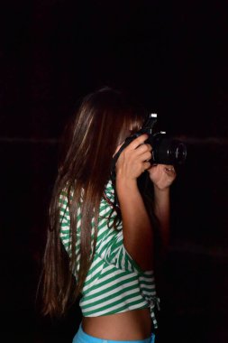 Siyah arka planda kamerası olan bir kız.