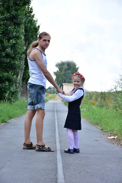 dad and daughter walk their backs along the road,