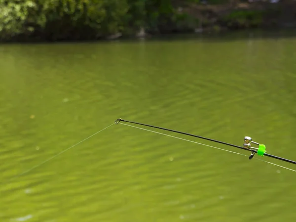 fishing pole with bells in the green calm river, bottom fishing line