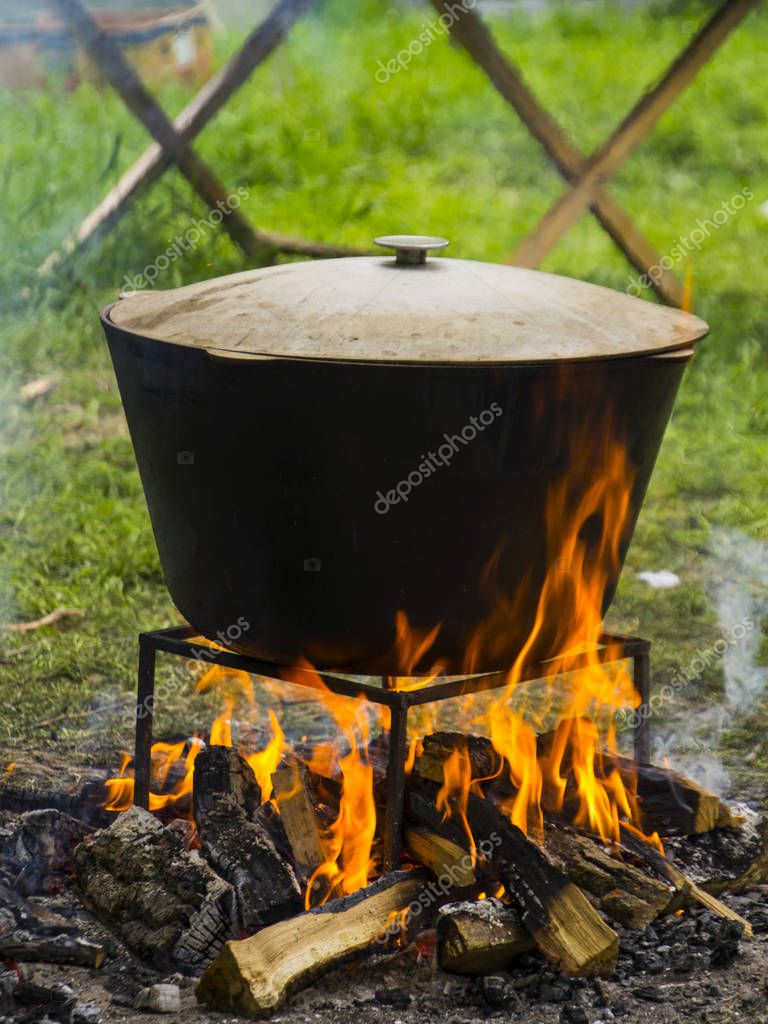 Food in a cauldron on a fire. Cooking outdoors in castiron cauldron