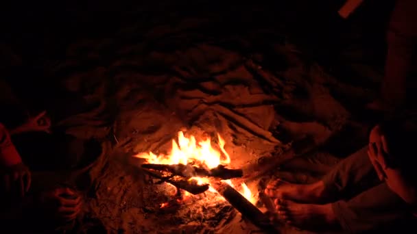 Homme dessinant sur du sable avec une bûche près du feu de camp de la plage. 4K UHD  . — Video