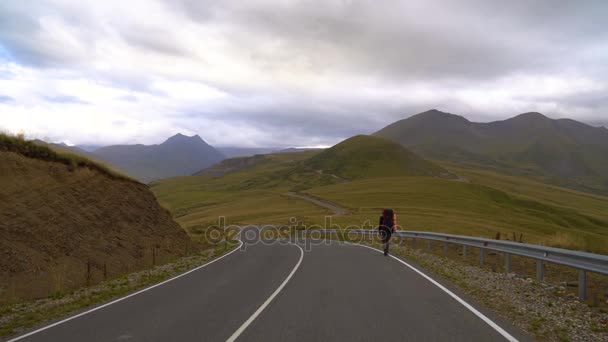 Мужчина идет по дороге в горах Кавказа. Автостоп 4K UHD — стоковое видео