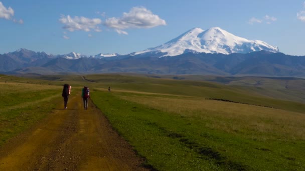 Dwóch facetów są piesze wycieczki przy drodze w góry Kaukazu. Przyjaciele idą do góry Elbrus 4k Uhd — Wideo stockowe