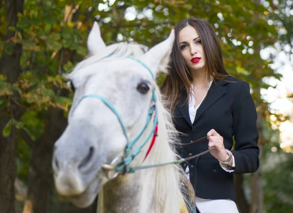Молодая брюнетка красотка-шутница девушка верхом на лошади в парке — стоковое фото