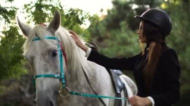 Genç esmer jokey kız parkta atı ile yürüyüş