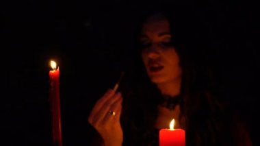 Kırmızı pelerin içinde mum ile çekici güzel esmer cadı mistik sonbahar ormanda çağrıştırıyor. büyücülük bir kalp, tavuk budu ve kirpi iğne ile