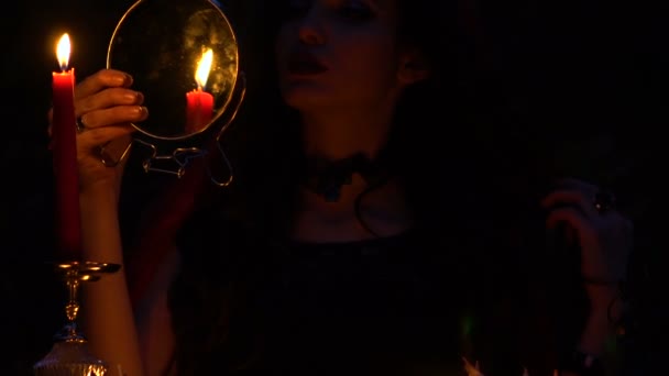 Vonzó gyönyörű barna boszorkány piros köpenyt idézi a misztikus őszi erdőben. boszorkányság szívvel, csirkecomb és sündisznó tűk — Stock videók