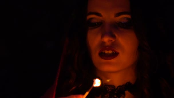 Attractive gorgeous brunette witch in red cloak conjures in the mystical autumn forest. witchcraft with a heart, chicken legs and porcupine needles — Stock Video