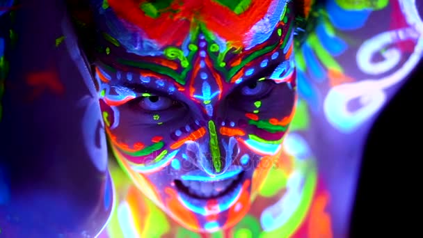 Yakın çekim duygular bir genç bodyarted avatar kız ultraviyole ışık. Kadın renk ışık yüzü. — Stok video