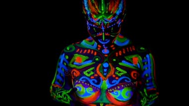Güzel genç seksi kız iç çamaşırı ittirir göğüslerini ultraviyole boya ile vücudunda. Renk ışık neon bodyart kızla.