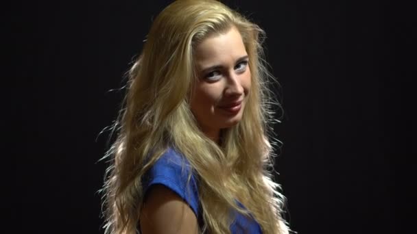 Schöne sexy blonde Mädchen in blauem Kleid flirtet und lädt Sie ein, mit ihr im Studio mit schwarzem Hintergrund gehen. — Stockvideo