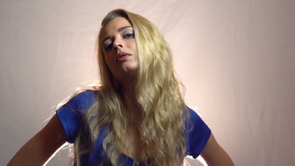 Belle fille blonde sexy en robe bleue séduire en studio avec un fond clair . — Video