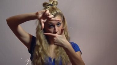 Mavi elbiseli güzel seksi sarışın kızı beyaz arka plan ile Studio çerçeve aracılığıyla arıyor. Fotoğrafçı işareti.