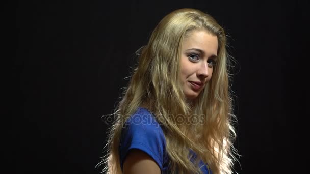 Schöne sexy blonde Mädchen in blauem Kleid zwinkert Ihnen im Studio mit schwarzem Hintergrund zu. — Stockvideo