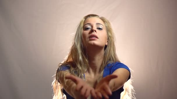 Vackra känslomässiga blond flicka i blå klänning vänligen att ge det till henne i Studio med ljus bakgrund. — Stockvideo