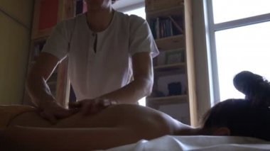 Masör profesyonel masaj oturumunda penceresinden gün ışığı alan üzerinde sıcak yağ ile genç kadın arkası Kneads. Ayurveda Abyanga Masaj.