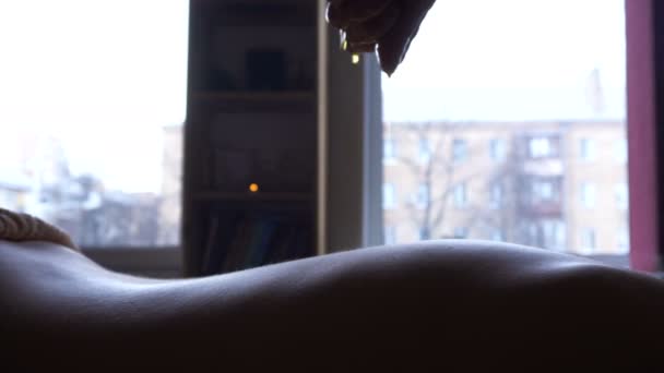Массажист наливает теплое масло на спину молодой девушки на сеансе профессионального массажа. Аюрведический массаж Абьянги . — стоковое видео
