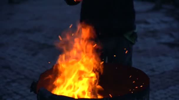 Mann wärmt Hände nahe Feuertonne. — Stockvideo