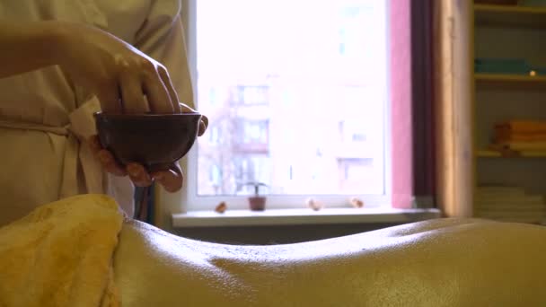 Masseur giet warme olie op de achterkant van Young man op Professional Massage sessie. Ayurvedic Abyanga massage. — Stockvideo