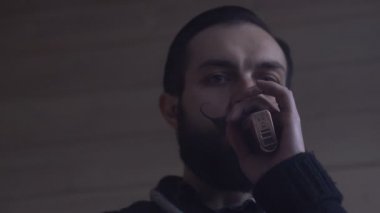 Sakal ve Mustages Vaping elektronik sigara olan genç adam. Vaper Hipster duman Buharlaştırıcı ve Exhals duman halkaları.