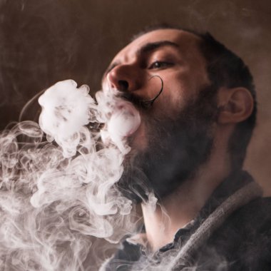 Sakal ve Mustages Vaping elektronik sigara olan adam. Vaper Hipster duman Buharlaştırıcı ve Exhals duman halkaları.