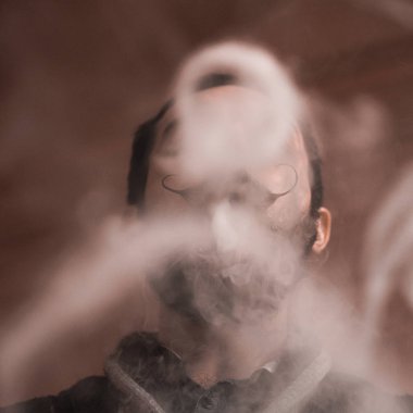 Sakal ve Mustages Vaping elektronik sigara olan adam. Vaper Hipster duman Buharlaştırıcı ve Exhals duman halkaları.