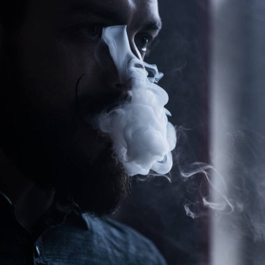 Sakal ve Mustages Vaping elektronik sigara olan adam. Vaper Hipster duman Buharlaştırıcı ve Exhals duman akış.