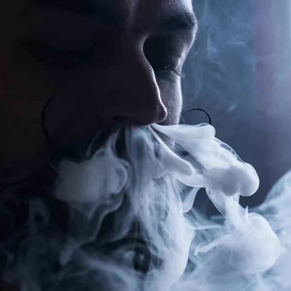 Sakal ve Mustages Vaping elektronik sigara olan adam. Vaper Hipster Buharlaştırıcı ve burun akışından Exhals duman duman.