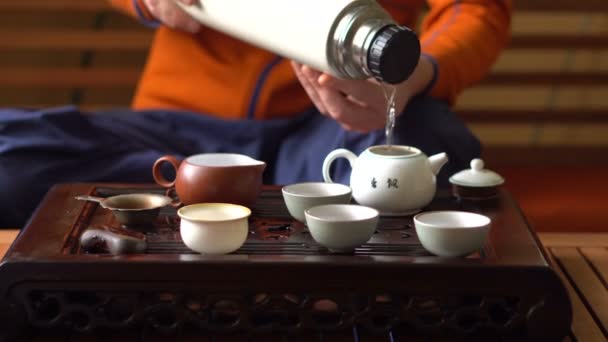 男は中国茶道でティーポットにお湯を注ぐします。お茶を飲みながらの機器を設定します。 — ストック動画