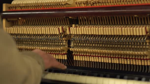 Руки старика в метро, играющего на фортепиано с открытыми механическими струнами и молотками — стоковое видео