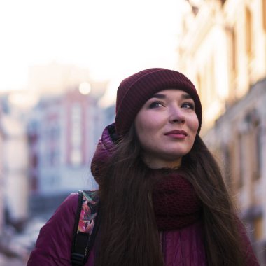 Güzel esmer kız mor kış ceket, şapka ve atkı, Avrupa Street tarafından kış yürüyüş giyiyor