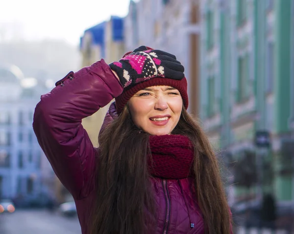 Çok gülümseyen esmer kız mor kış ceket, şapka ve atkı, Avrupa Street tarafından kış yürüyüş giyiyor — Stok fotoğraf
