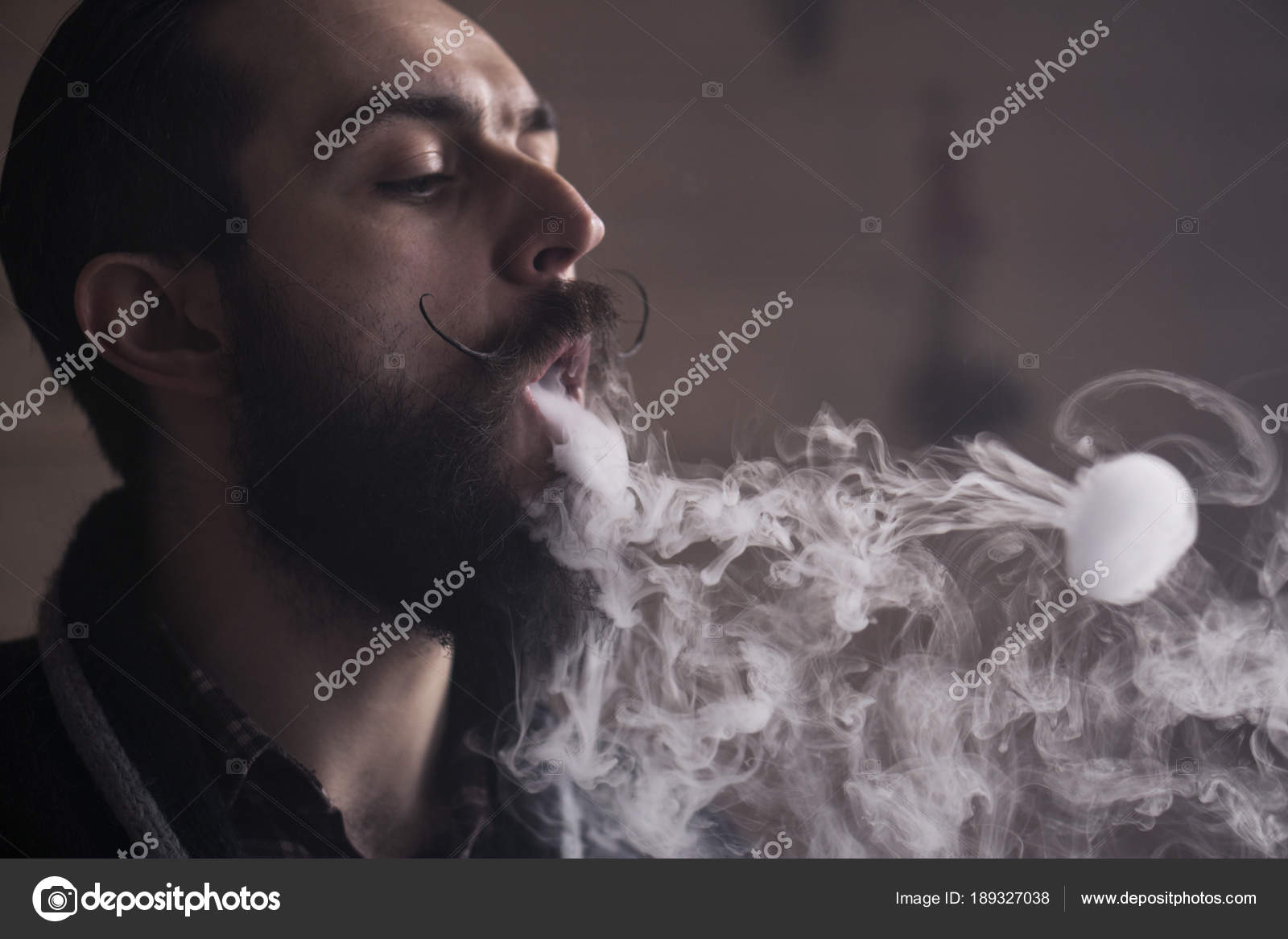 Man with Beard and Mustages Vaping an Electronic Cigarette. Vaper Hipster  Smoke Vaporizer and Exhals Smoke Rings. Stock Photo by ©tomasadzke 189327038