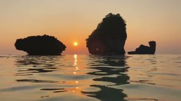 Романтический закат на побережье Индийского океана. Скальные камни поднимаются над водой, речки на поверхности моря и отражение скалы и солнца. Nui Bay, Phi-Phi, Фаби, Таиланд . — стоковое видео