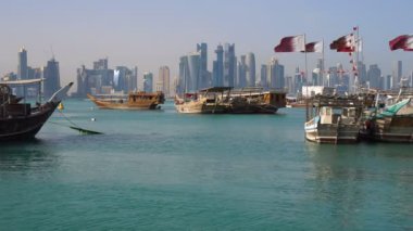 Yaş karışımı. Doha Modern şehir manzarası görünümü. Gün atış, Katar, Orta Doğu. Geleneksel ahşap Katar tekneler Basra Körfezi'nin temiz masmavi suda Corniche Broadway sahilinde Katar bayraklı.