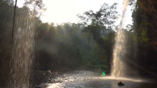 Ver formulario Café bajo la pintoresca cascada en las selvas a la hora de la tarde. El agua cae en la piscina a través de los rayos del sol en el Parque Nacional Khao Yai, Tailandia . — Vídeo de stock