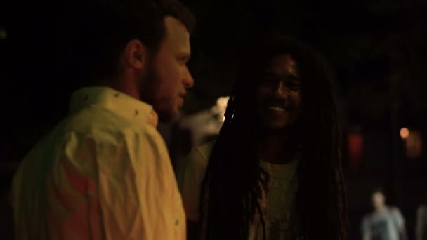 Thailand, Krabi, 20 februari 2018. Twee verschillende mensen: Kaukasische en Afro Amerikaanse Rasta met Dreadlocks, onder een gesprek over de nacht straat in de buurt van de Rasta-Bar. — Stockvideo