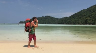 Sırt çantası turist onun Harp ederken yürüyerek sahil şeridi sıcak su Azure tropikal lagün üzerinde oynarken mutlu uzun yürüyüşe çıkan kimse adam