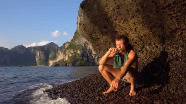 Cesur maceracı adam oynarken Hapr yalınayak yamaç, keskin Adası kireçtaşı mağara, Krabi, Tayland ile Rock Railey Beach arka plan üzerinde olduğunu.